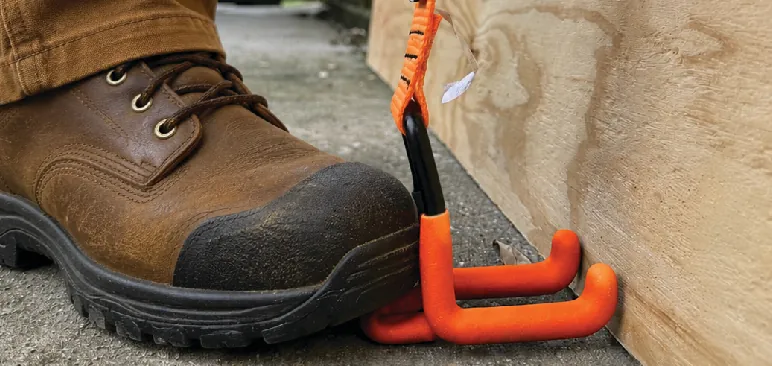 Work boot stepping on the kick plate of the orange hook under the bottom edge of a panel